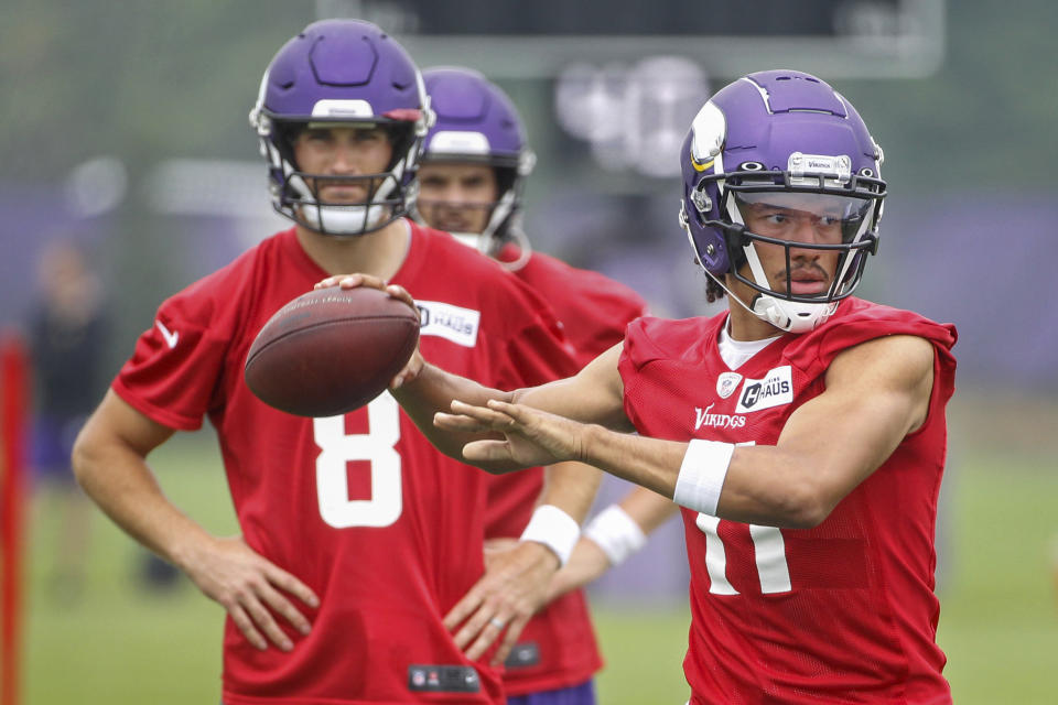 Minnesota Vikings quarterback Kellen Mond (11) throws a pass in front of quarterback Kirk Cousins (8) during NFL football training camp Friday, July 30, 2021, in Eagan, Minn. (AP Photo/Bruce Kluckhohn)