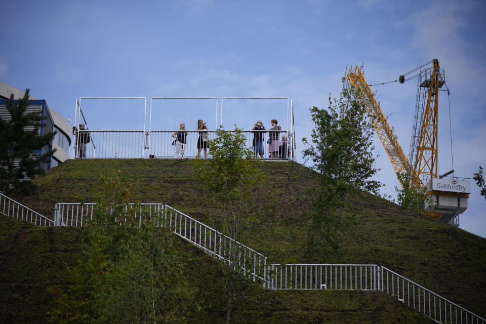 Visitors stand in the viewing area of the newly built "Marble Arch Mound" after it was opened to the public next to Marble Arch in London, Tuesday, July 27, 2021. The temporary installation commissioned by Westminster Council and designed by architects MVRDV has been opened as a visitor attraction to try and entice shoppers back to the adjacent Oxford Street after the coronavirus lockdowns. (AP Photo/Matt Dunham)