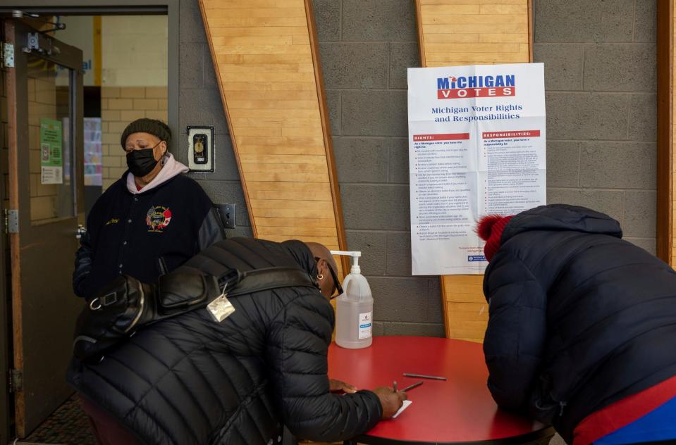 From left, Andrei Chapman stands next to Anthony Morson and Mary Chapman as they fill out information cards before voting inside Osborn High School during the presidential primary in Detroit on Tuesday, Feb. 27, 2024.