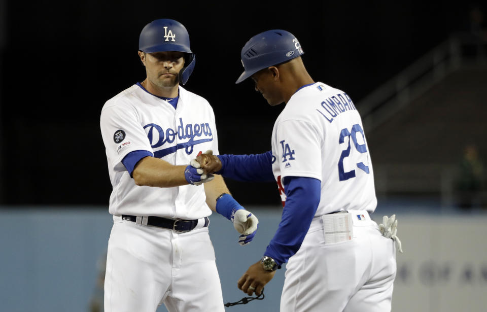 Los Angeles Dodgers' A.J. Pollock, left, shakes hands with first base coach George Lombard after hitting a bases-loaded single against the Arizona Diamondbacks during the third inning of a baseball game Friday, March 29, 2019, in Los Angeles. (AP Photo/Marcio Jose Sanchez)