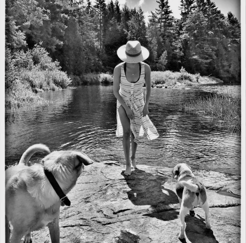 Meghan stands by a natural pool with her dogs Bogart and Guy.