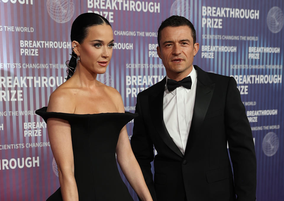 Katy Perry and Orlando Bloom at the Breakthrough Prize event. Katy is wearing an off-shoulder gown, and Orlando is in a classic black tuxedo