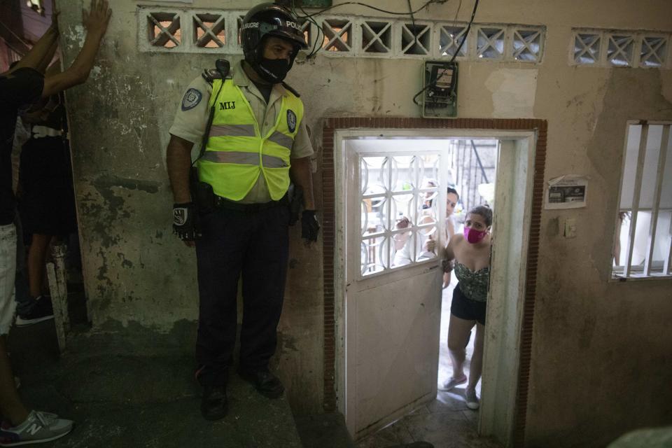 Una mujer cierra la puerta de su casa mientras la policía municipal y los soldados de la Guardia Nacional patrullan en el barrio Petare de Caracas, Venezuela, el viernes 7 de agosto de 2020, para asegurarse de que los residentes estén cumpliendo con las restricciones de movilidad ordenadas para contener la propagación del nuevo coronavirus. (Foto AP/Ariana Cubillos)