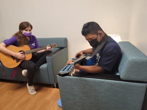 Christy Medley of JoyRx Music works with Lian Lott, 15, on how to play the guitar in a new program that brings lessons to kids with complex medical diagnoses.