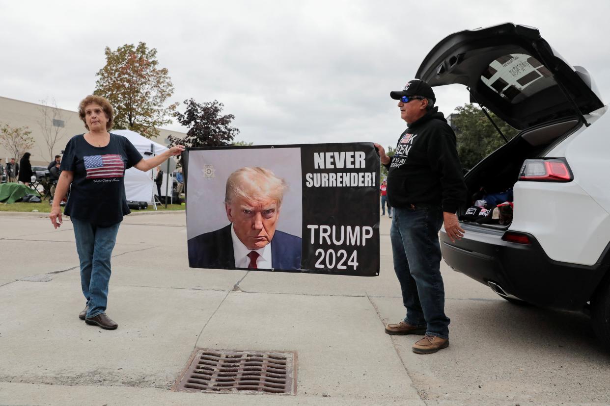 Trump supporters hold a banner in Clinton Township, Michigan ahead of his arrival in the state. (REUTERS)