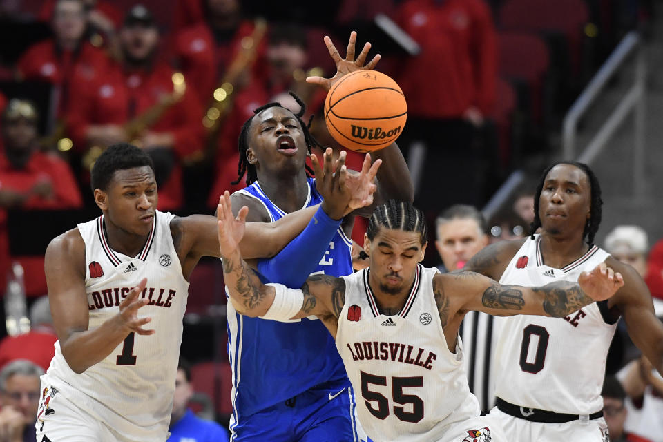 Duke forward Mark Mitchell (25), center, battles Louisville guard Curtis Williams (1) and guard Skyy Clark (55) for a loose ball during the second half of an NCAA college basketball game in Louisville, Ky., Tuesday, Jan. 23, 2024. Duke won 83-69. (AP Photo/Timothy D. Easley)