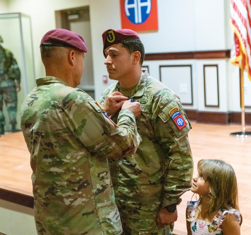 Maj. Gen. Christopher LaNeve, commander of the 82nd Airborne Division, pins the Soldier's Medal on 1st Lt. Joseph Guerra, while Guerra's daughter watches during a ceremony Friday, Aug. 11, 2023, in the division's Hall of Heroes on Fort Liberty.