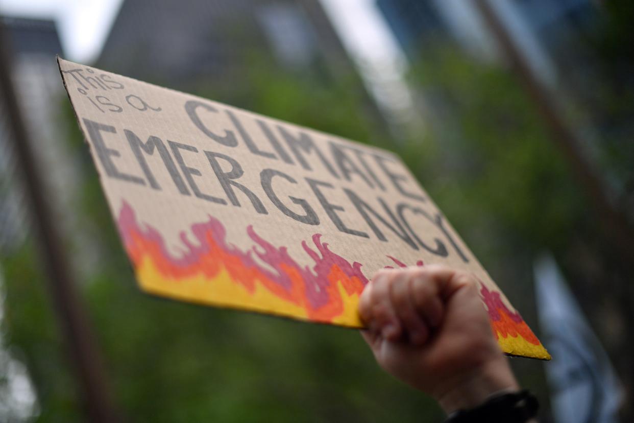 An attendee holds up a placard at a climate protest rally in Sydney on December 11, 2019. - Up to 20,000 protesters rallied in Sydney on December 11 demanding urgent climate action from Australia's government, as bushfire smoke choking the city caused health problems to spike. (Photo by Saeed KHAN / AFP) (Photo by SAEED KHAN/AFP via Getty Images)