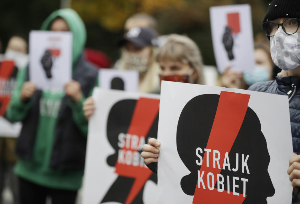 Women's rights activists with posters of the Women's Strike action protest against recent tightening of Poland's restrictive abortion law in front of the parliament building as inside, guards had to be used to shield right-wing ruling party leader Jaroslaw Kaczynski from angry opposition lawmakers, in Warsaw, Poland, on Tuesday, Oct. 27, 2020. Massive nationwide protests have been held ever since a top court ruled Thursday that abortions due to fetal congenital defects are unconstitutional. Slogan reads 'Women’s Strike'. (AP Photo/Czarek Sokolowski)