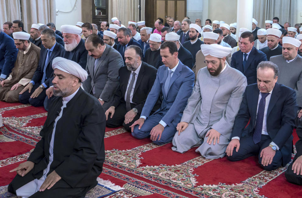 In this photo released by the Syrian official news agency SANA, Syrian President Bashar Assad, third from right, prays on the first day of the the Eid al-Adha, at Afram Mosque in Damascus, Syria, Sunday, Aug. 11, 2019. State news agency SANA showed Assad attending the payers early Sunday at Afram Mosque along with top officials including the prime minister and the country's grand mufti. (SANA via AP)