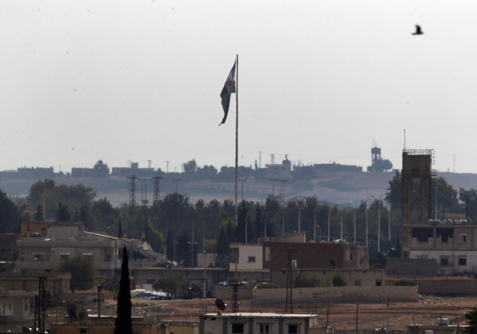 FILE - In this Oct. 22, 2019 photo taken from the Turkish side of the border between Turkey and Syria, in Akcakale, Sanliurfa province, southeastern Turkey, Syria's opposition flag flies on a pole in Tal Abyad, Syria. Turkey's Defense Ministry says a car bomb went off in Tal Abyad, killing several civilians. The ministry says others were wounded when the bomb exploded Saturday, Nov. 2 in central Tal Abyad, which was captured last month by Turkey-backed opposition gunmen from Kurdish-led fighters. (AP Photo/Lefteris Pitarakis, File)