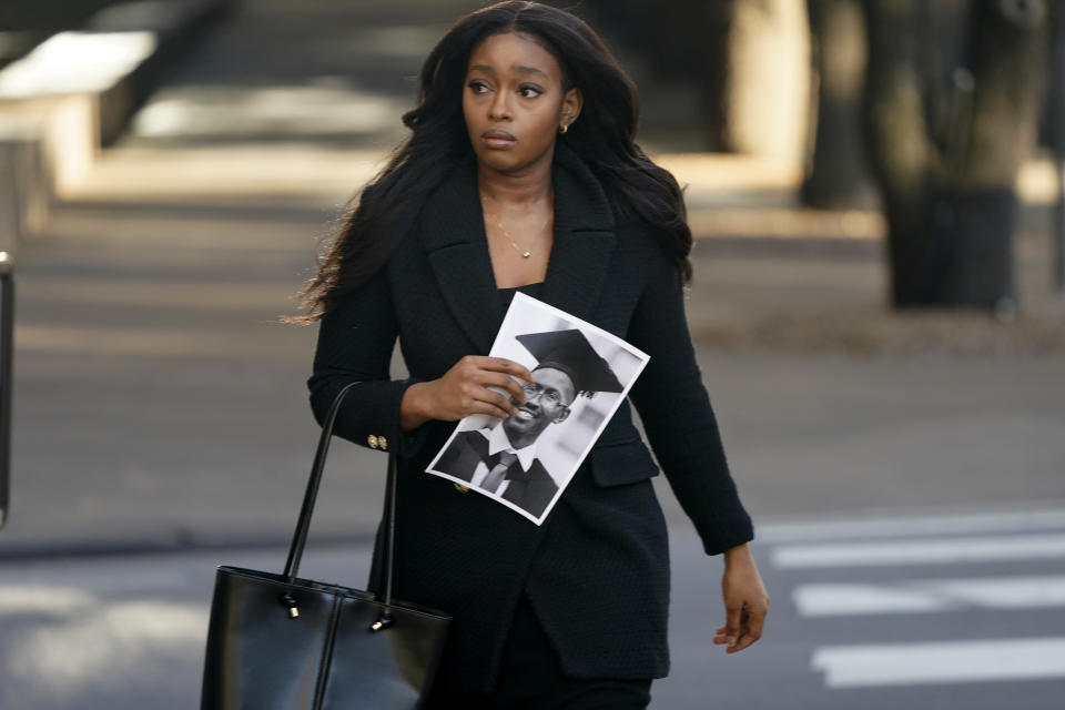 Zipporah Kuria, of London, carries a photo of her deceased father Joseph Waithaka as she walks into federal court for the Boeing arraignment hearing in Fort Worth, Texas, Thursday, Jan. 26, 2023. Waithaka was killed in 2019 crash of a Boeing 737 Max airliner. (AP Photo/LM Otero)