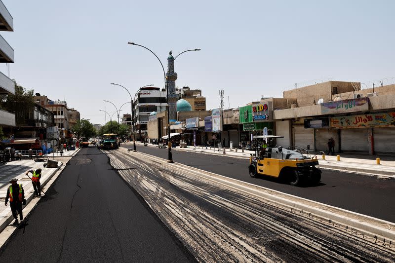 Iraqi workers lay asphalt as a Al-Karada street is paved in Baghdad