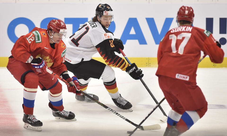 Ilya Kruglov, left, and Maxim Sorokin, right, of Russia and Moritz Seider of Germany fight for the puck during the 2020 IIHF World Junior Ice Hockey Championships Group B match between Russia and Germany in Ostrava, Czech Republic, on Tuesday Dec. 31, 2019. (Jaroslav Ozana/CTK via AP)