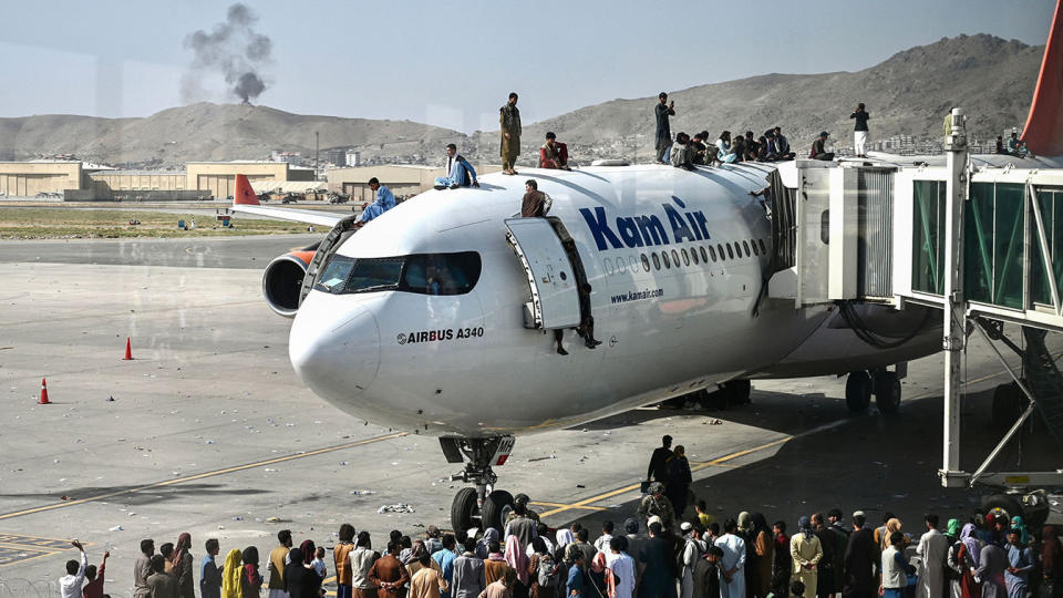 Afghan people climb atop a plane at the airport in Kabul, Afghanistan, on Monday. (Photo by Wakil Koshar/AFP via Getty Images)