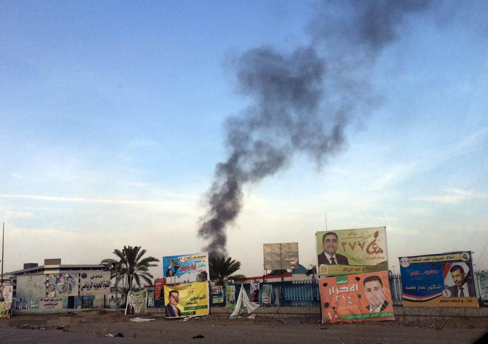 Smoke rises above campaign posters after a series of bombs that exploded Friday, April 25, 2014 at a campaign rally for a Shiite group in Baghdad, Iraq, ahead of the country's parliamentary election. The blasts killed and wounded dozens, officials said. (AP Photo/Karim Kadim)