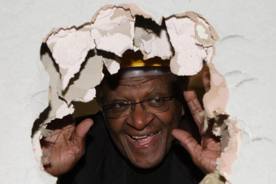 Desmond Tutu peers through a hole he knocked in a wall at St Luke’s Hospital for the Clergy, central London, in 2006 (Rebecca Reid/PA) (PA Wire)