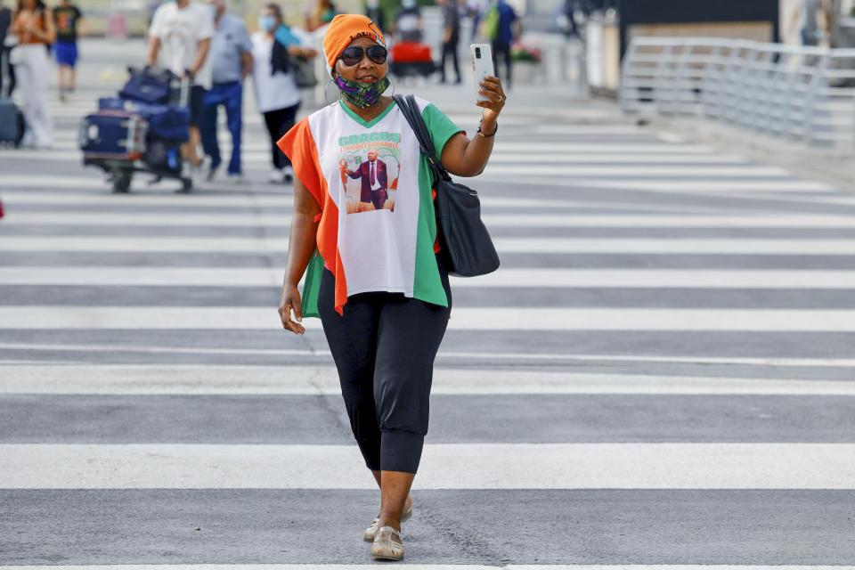 A supporter of former Ivory Coast President Laurent Gbagbo takes photos with her smartphone at the Brussels international airport in Brussels, Thursday, June 17, 2021. The former Ivory Coast president Laurent Gbagbo is returning home to Ivory Coast for the first time in nearly a decade, after his acquittal on war crimes charges was upheld at the International Criminal Court earlier this year. (AP Photo/Olivier Matthys)