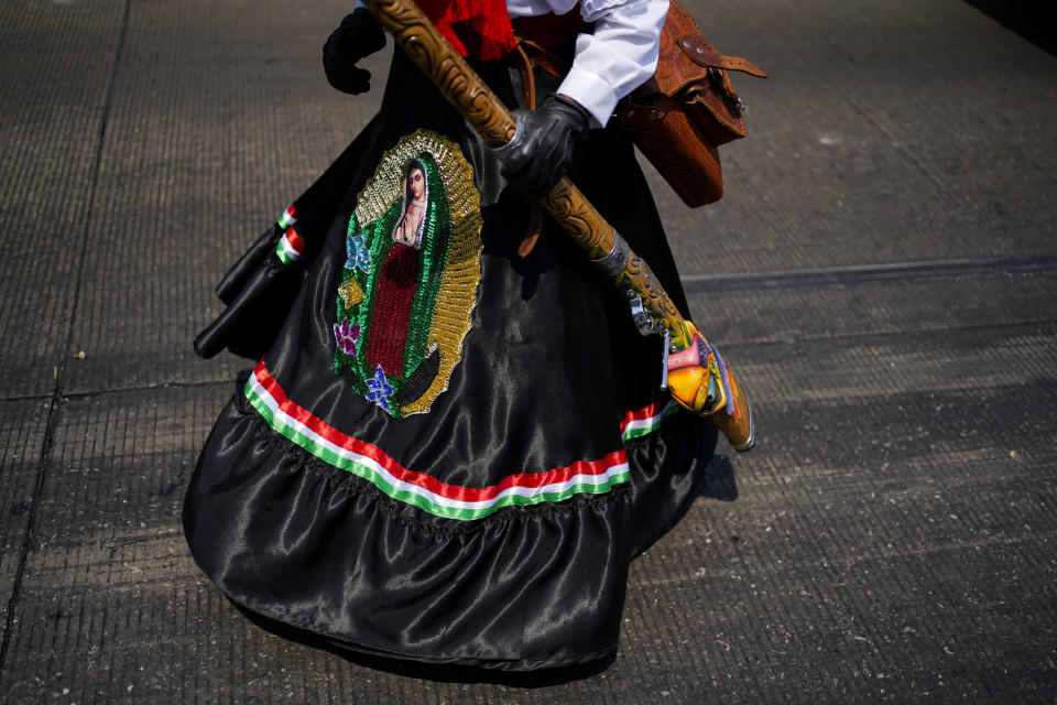A woman with an image of the Virgin of Guadalupe on her skirt dances during a re-enactment of The Battle of Puebla as part of Cinco de Mayo celebrations in the Peñon de los Baños neighborhood of Mexico City, Thursday, May 5, 2022. Cinco de Mayo commemorates the victory of an ill-equipped Mexican army over French troops in Puebla on May 5, 1862. (AP Photo/Eduardo Verdugo)