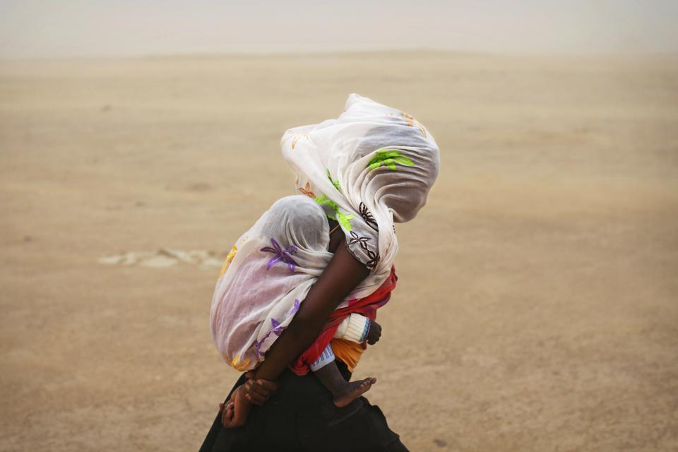 RNPS - PICTURES OF THE YEAR 2013 - A woman carrying her baby and wrapped with a shawl walks through a sandstorm in Timbuktu July 29, 2013. REUTERS/Joe Penney (MALI - Tags: SOCIETY ENVIRONMENT TPX)