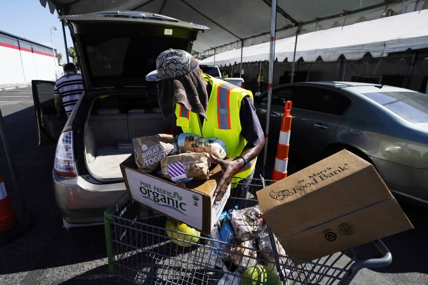 A volunteer fills up a vehicle with food boxes at the St. Mary's Food Bank Wednesday, June 29, 2022, in Phoenix. The food banks are struggling to meet the growing need even as federal programs provide less food to distribute, grocery store donations wane and cash gifts don't go nearly as far. (AP Photo/Ross D. Franklin)