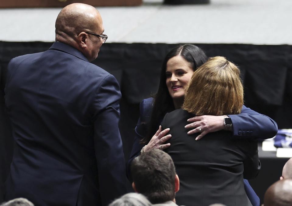 Kelly Weeks, center, the widow of slain Deputy U.S. Marshal Thomas Weeks Jr., hugs attendees at wldher husband's memorial service as she went to the podium to speak at Bojangles Coliseum in Charlotte, N.C. on Monday, May 6, 2024. (Jeff Siner/The Charlotte Observer via AP)