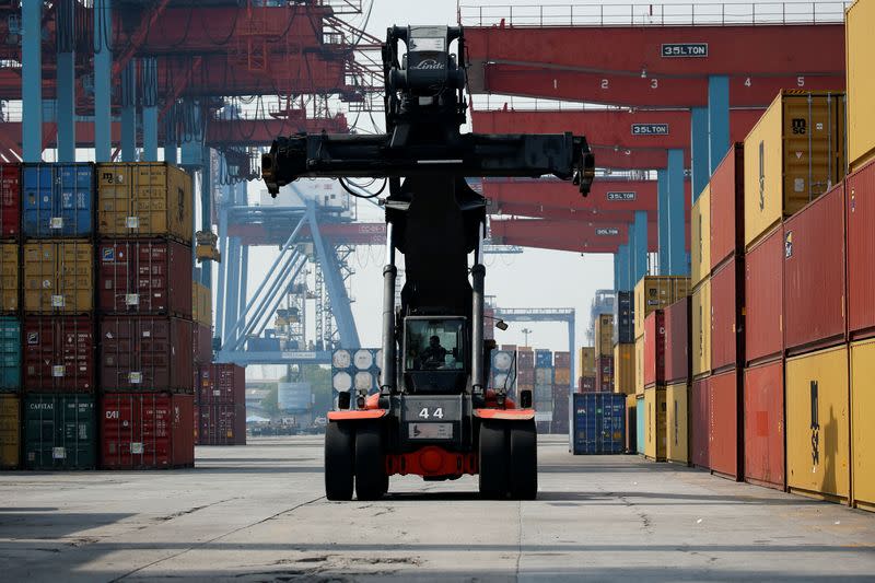 FILE PHOTO: A worker drives a reach taker vehicle past stacks of containers at the IPC Containter Terminal of Tanjung Priok port in Jakarta