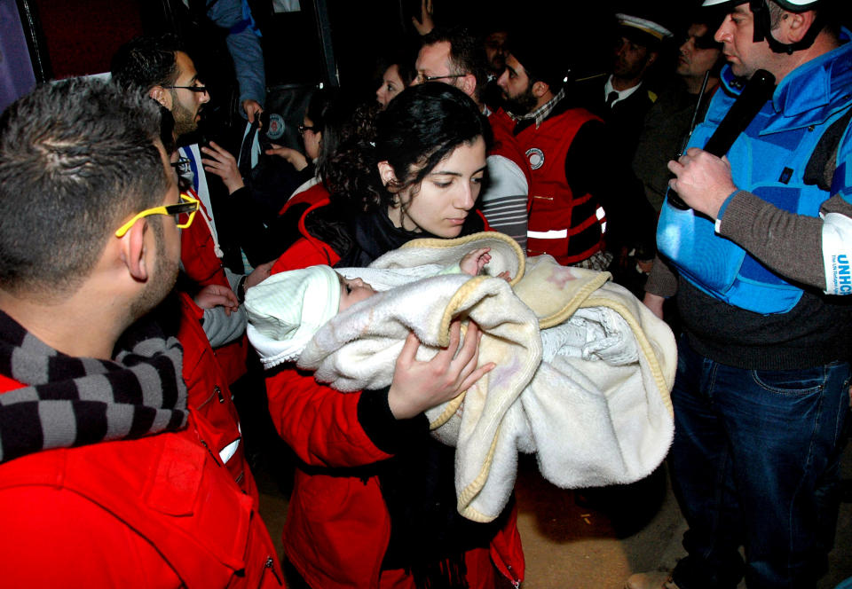 FILE - In this Monday Feb. 10, 2014 file photo, released by the Syrian official news agency SANA, a Syrian Arab Red Crescent member carries a baby to a bus to evacuate the battleground city of Homs, Syria. Weeping children begged for food in the streets and women picked grass growing in the cracks of the sidewalks to eat as hunger gripped residents of rebel-held neighborhoods of the Syrian city of Homs blockaded for nearly two years by the military, according to a rare first-hand account by a man evacuated during a truce this week. (AP Photo/SANA, File)