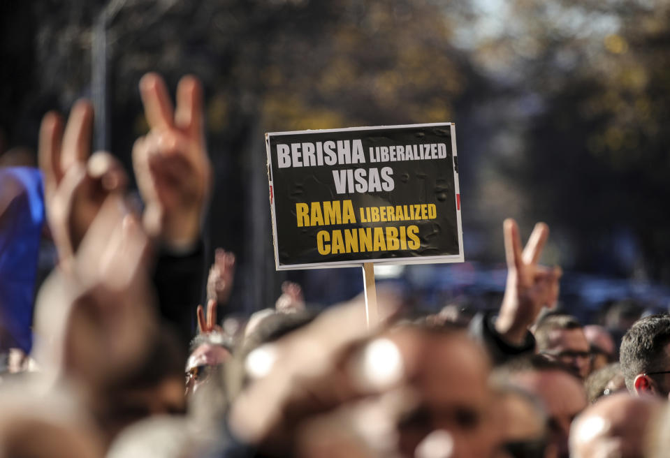 A supporter of the center-right Democratic Party holds a placard during an anti-government rally outside the Parliament building in Tirana, Albania, Monday, Dec. 18, 2023. Albanian opposition have protested against the government's it accuses of corruption while a parliamentary commission discusses on immunity for its leader Sali Berisha. (AP Photo/Armando Babani)