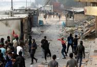 Iraqi demonstrators throw stones towards Iraqi security forces during the ongoing anti-government protests, in Baghdad