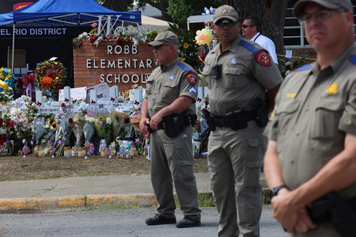 Texas Highway Patrol officers in front of a memorial at Robb Elementary School.