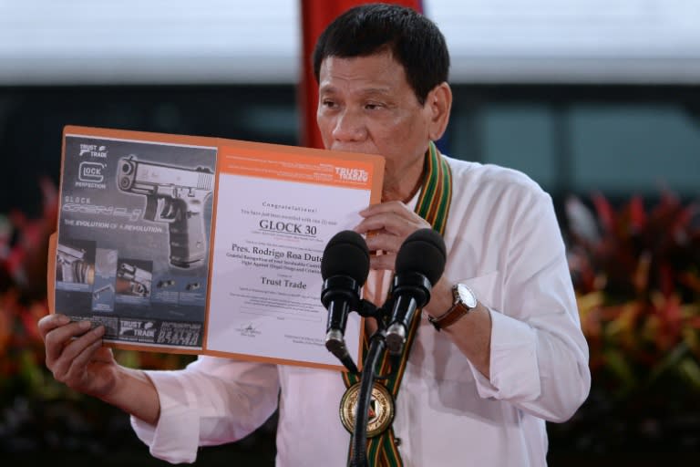 Philippine President Rodrigo Duterte holds up a certificate showing a Glock 30 handgun, awarded to him by a Philippine firearms importer for his fight against illegal drugs, in Manila on October 4, 2016