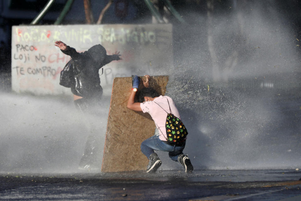 Demonstrators react as police water cannon is deployed during a protest against Chile's state economic model in Santiago, Chile on Oct. 28, 2019. (Photo: Edgard Garrido/Reuters)