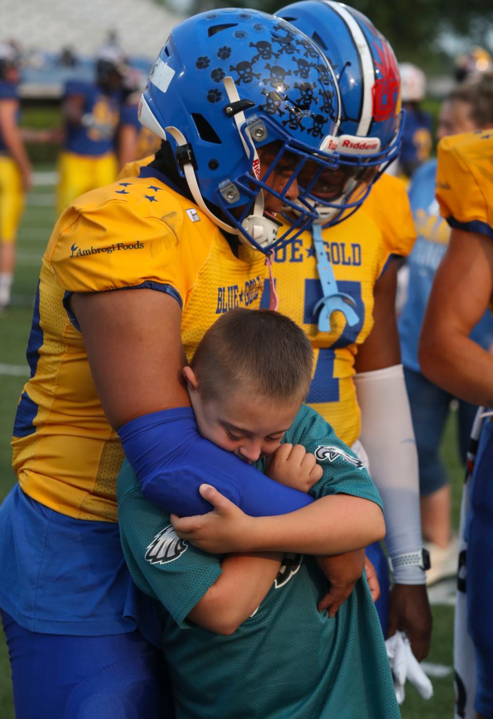 Game buddy Levin Wolf, 10 of Townsend, grabs on to Middletown's Michael Pearson as Wolf meets up with players before Blue's 21-12 win in the DFRC Blue-Gold All-Star Game Friday, June 16, 2023 at Delaware Stadium.