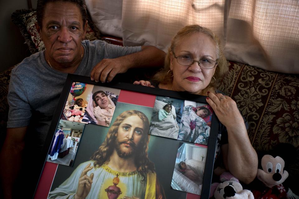 Juan Manuel González (izq) y María González Muñoz posan el 4 de septiembre en San Juan con un retrato de Jesús y fotos de su hermana Ramona, una mujer incapacitada que falleció a los 59 años de una septicemia. Los hermenos dicen que murió a raíz de una úlcera que no fue debitamente tratada después del paso del huracán María por Puerto Rico. (AP Photo/Ramón Espinosa)