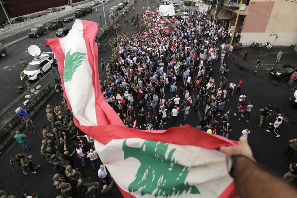 A Lebanese flag is waved through the air as anti-government protesters demonstrate in the town of Jal el-Dib north of Beirut, Lebanon, Wednesday, Oct. 23, 2019. Lebanese troops have moved in to open several major roads in Beirut and other cities, scuffling in some places with anti-government protesters who had blocked the streets for the past week. (AP Photo/Hassan Ammar)