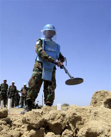 A Cambodian mine clearing expert uses a metal detector for explosives in a mine hazard area in the United Nations controlled buffer zone, east of the Cypriot capital Nicosia April 23, 2014. REUTERS/Andreas Manolis