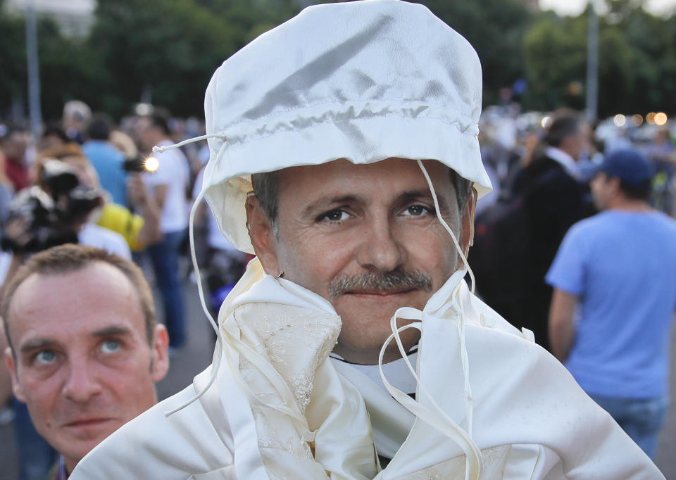 A man looks at a cardboard depiction of Liviu Dragnea, the leader of the ruling Social Democratic party, as hundreds celebrate his sentencing to prison outside the government headquarters in Bucharest, Romania, Monday, May 27, 2019. Romania's most powerful politician was sentenced Monday to 3 and a half years in prison for official misconduct in a graft case. (AP Photo/Vadim Ghirda)