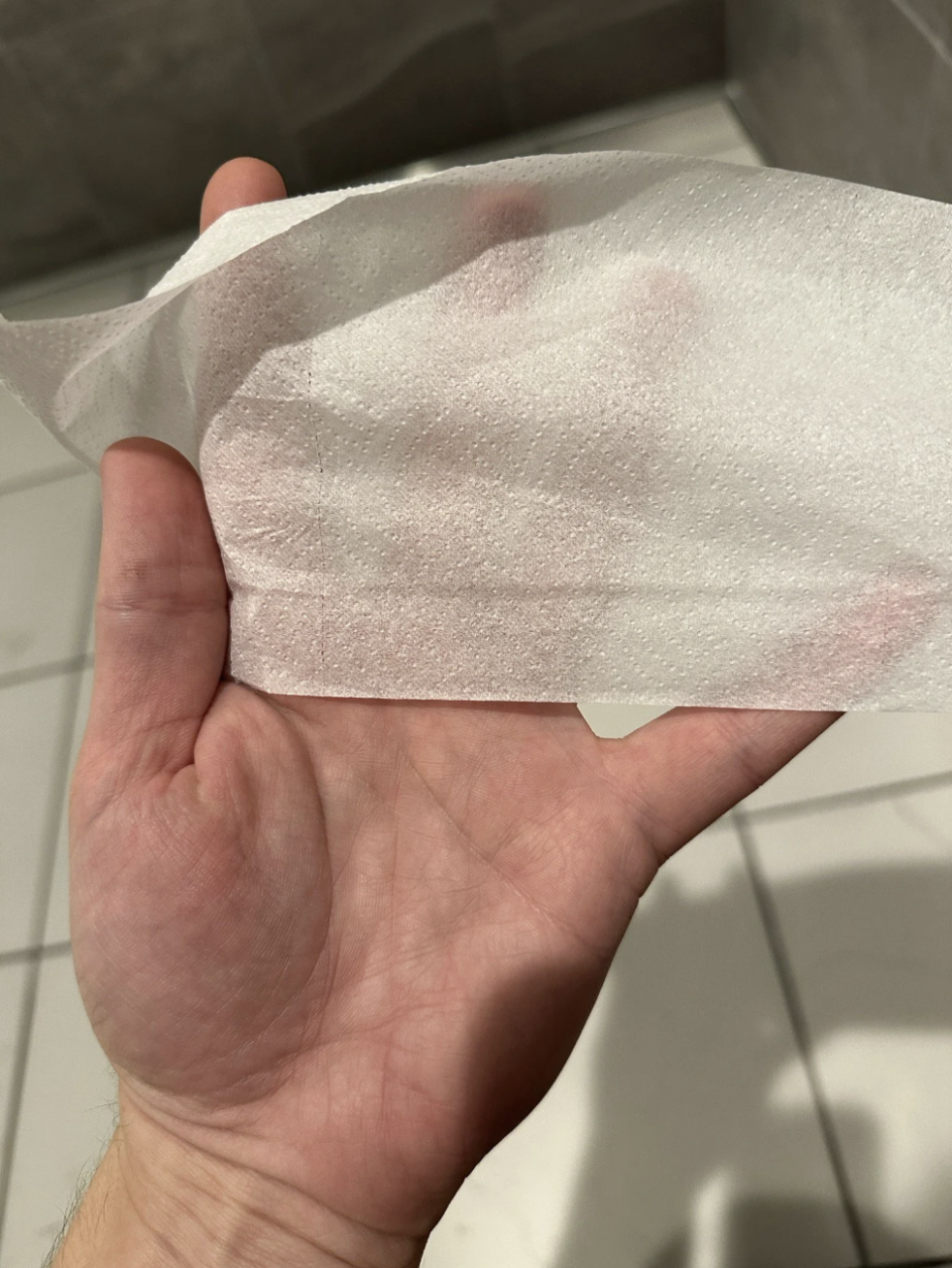 The toilet paper is so thin, you can see the person's hand on the other side of it