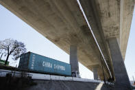 FILE- In this July 2, 2018, file photo, a truck carrying a cargo container drives under the Gerald Desmond Bridge under construction in Long Beach, Calif. China on Tuesday, Sept. 18, announced a tariff hike on $60 billion of U.S. products in response to President Donald Trump's latest duty increase in a dispute over Beijing's technology policy. (AP Photo/Jae C. Hong, File)