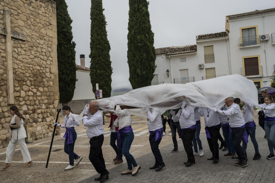 Members of the "Vera Cruz" Catholic brotherhood carry a figure of Jesus Christ, covered with a plastic sheet to protect it from rain, during a Holy Week procession in the southern town of Quesada, Spain, Friday, March 29, 2024. (AP Photo/Bernat Armangue)
