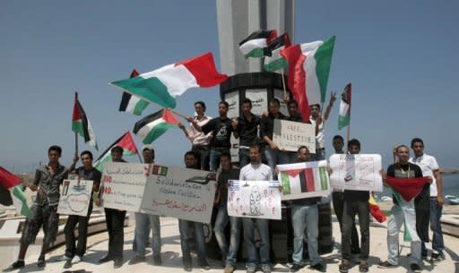 Palestinians wave flags and hold banners during a rally in Gaza City in support of the international Freedom Flotilla hoping to breach Israel's sea blockade on the Gaza Strip, on July 6, 2011