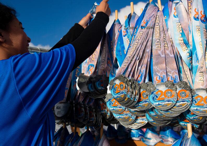 Joeclyn Alvarez arranges medals for finishers of the Orange County Marathon so they will be ready to hand out as they cross the finish line in Costa Mesa on Sunday, May 5.