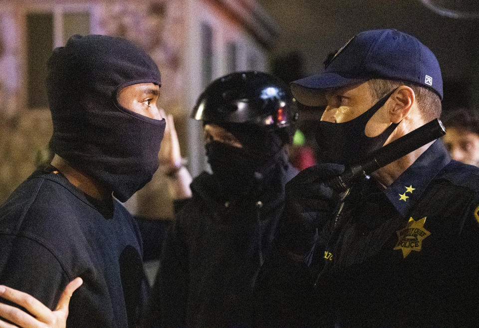 A demonstrator talks to an Oakland police officers during a protest against police brutality in Oakland, Calif., on Friday, April 16, 2021. (AP Photo/Ethan Swope)