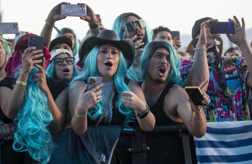 Men and women in the signature blue wigs of Karol G