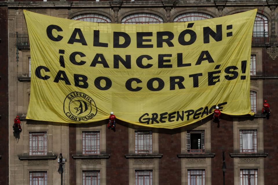 Greenpeace activists hang a banner from a building in front of the Zocalo, Mexico City's main plaza,Tuesday March 27, 2012. Greenpeace is protesting plans to build a resort in Cabo Pulmo on the Baja California peninsula. The banner reads in Spanish; "Calderon: Cancel Cabo Cortes," the commercial name of the planned resort. (AP Photo/Marco Ugarte)