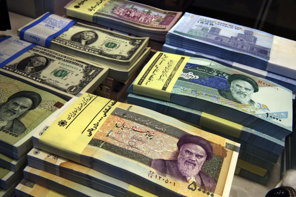 FILE - In this April 4, 2015 file photo, Iranian and U.S. banknotes are on display at a currency exchange shop in downtown Tehran, Iran. Iran's president has sent a bill to parliament that would cut four zeroes from value of the nation's sanctions-battered currency, the rial. Semi-official news agencies reported the news on Wednesday, Aug. 21, 2019, saying President Hassan Rouhani sent the bill with urgency to the parliament to consider. Iran's rial has been hammered by the effects of increasing U.S. sanctions on the country. (AP Photo/Vahid Salemi, File)