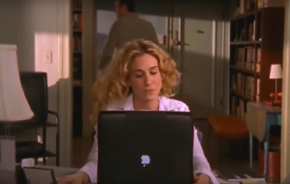 Carrie Bradshaw at her home desk typing away on her computer in "Sex and the City"