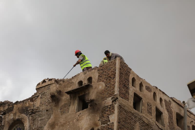 Workers demolish a building damaged by rain in the UNESCO World Heritage site of the old city of Sanaa