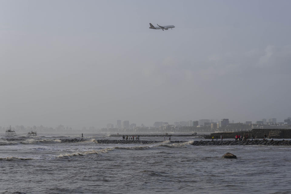 A passenger plane flies as high tide waves hit the Arabian Sea coast at Juhu Koliwada in Mumbai, India, Monday, June 12, 2023. Cyclone Biparjoy, the first severe cyclone in the Arabian Sea this year is set to hit the coastlines of India and Pakistan Thursday. (AP Photo/Rafiq Maqbool)